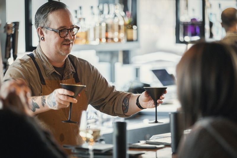 Bartender handing cocktails to guests at the bar
