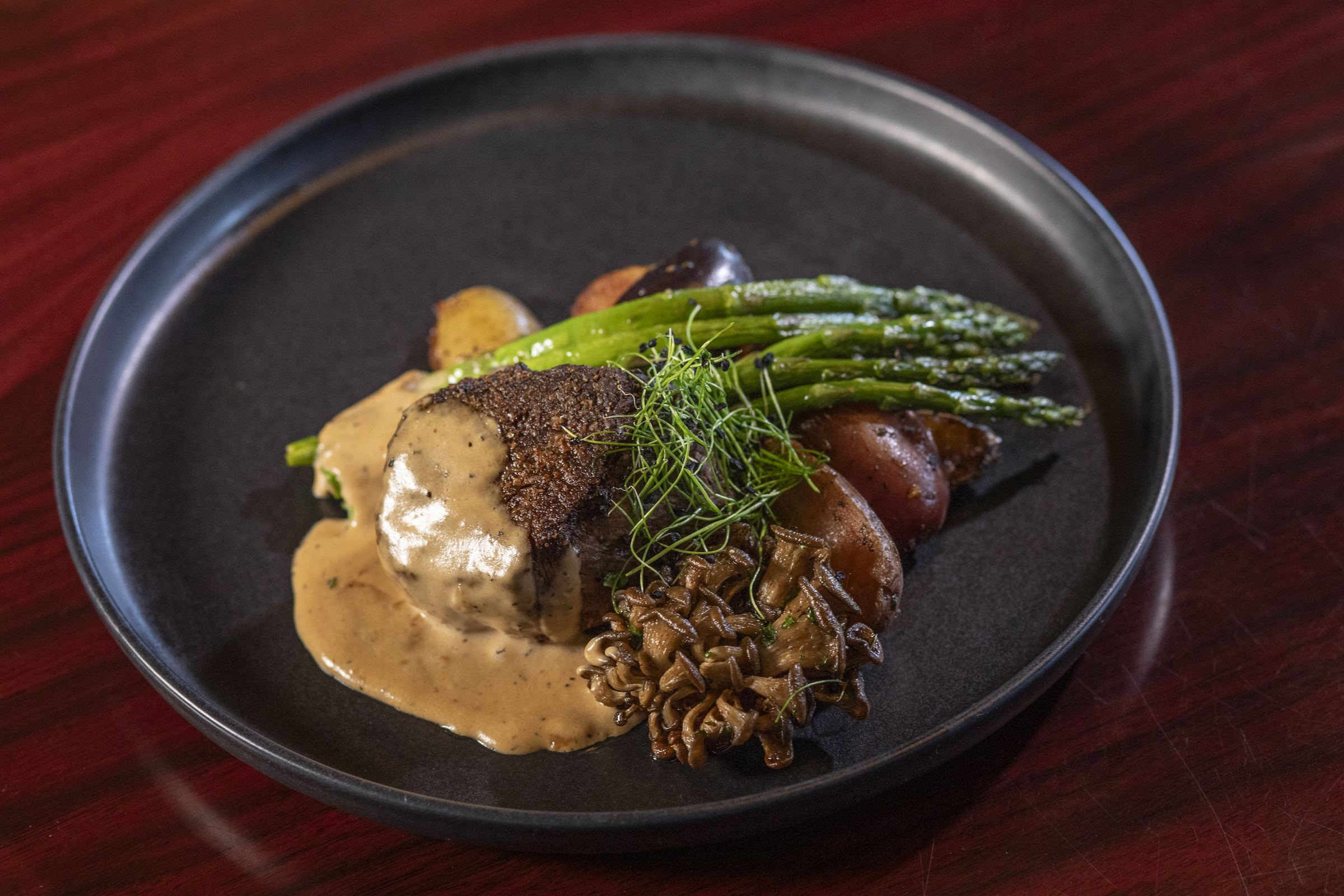 A plated steak with asparagus and mushrooms